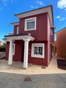 una casa roja con columnas blancas en Altaona Comfort & Calidad Villa, en Murcia
