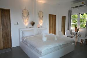 a white bedroom with a large white bed with two candles at Bao Village in Haad Yao