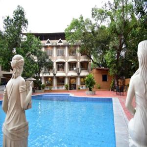 Aron Resort Lonavala - Near Old Mumbai Pune Highway في لونافالا: مسبح به تماثيل أمام المبنى