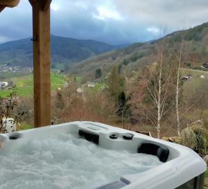 uma banheira cheia de água com montanhas ao fundo em Au chalet de JO em Muhlbach-sur-Munster