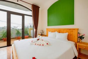 a bedroom with a white bed with a green wall at Sea and Sand Hotel in Hoi An