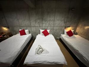 two beds in a room with white and red pillows at OYO 560 Chang Hostel Suvarnabhumi in Bangkok