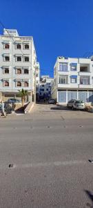 a large white building with cars parked in a parking lot at Dar jilali in Taghazout