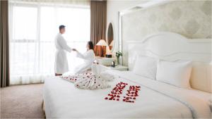 Muong Thanh Grand Quang Tri Hotel في Quang Tri: رجل وامرأة في غرفة فندق