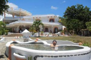 una mujer en un jacuzzi frente a una casa en Flintstone cave house, en Poctoy