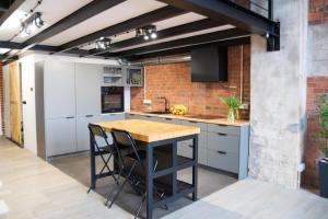 an industrial kitchen with white cabinets and a brick wall at RedCity LOFT 309 in Żyrardów