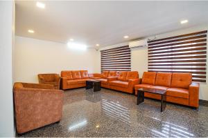 a waiting room with orange couches and tables at FabHotel Greenwood Xpress Inn - Nr Manipal Hospital in Bengaluru