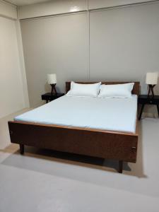 a large bed in a room with two lamps at HeiJo's Homestay in Jowai