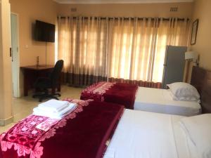 a hotel room with two beds and a desk at A boutique lodge situated in a serene environment - 2029 in Harare
