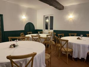 Gîte Les 27 في سان دوني لي فيرمونت: غرفة مع طاولات وكراسي مع مفارش بيضاء