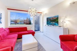 sala de estar con muebles de color rojo y ventana grande en Miky Apartmán Klínovec Garden en Loučná pod Klínovcem