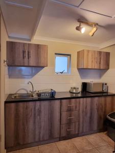 a kitchen with wooden cabinets and a sink at Private Guest Suite with 24hr Electricity, East London in East London