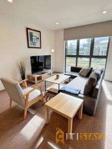 a living room with a couch and a tv at Bright in Braddon! 1 bd 1bth Apt in Canberra