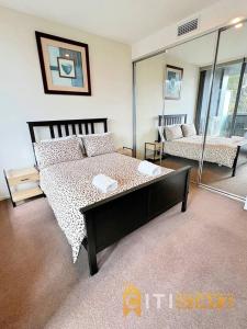 a bedroom with a large bed and a mirror at Bright in Braddon! 1 bd 1bth Apt in Canberra