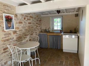 - une cuisine avec une table, des chaises et un évier dans l'établissement Une Maison de campagne en Bourgogne du Sud, à Tournus