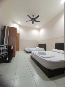 two beds in a room with a ceiling fan at Seaview Promenade Homestay Dungun in Dungun