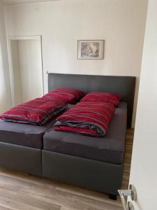 Bett mit roten Kissen auf einem Zimmer in der Unterkunft Schwalbenhof in Westerstede