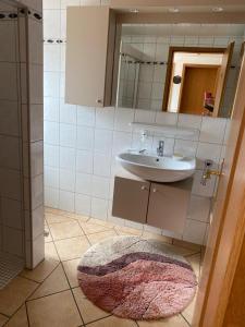 ein Badezimmer mit einem Waschbecken, einem Spiegel und einem Teppich in der Unterkunft Schwalbenhof in Westerstede