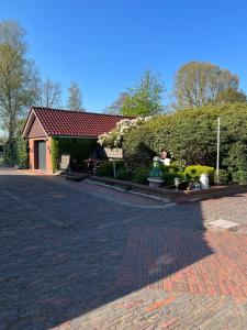 a brick parking lot with a building with a hedge at Schwalbenhof in Westerstede