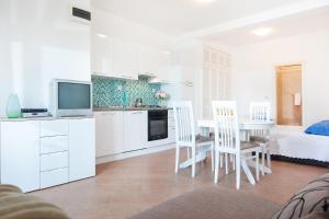 a white kitchen with a table and chairs and a bed at Villa Helena in Podgora