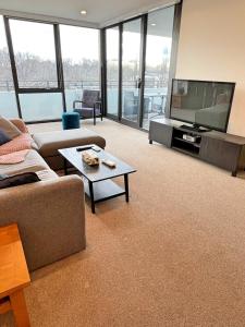 uma sala de estar com um sofá e uma televisão de ecrã plano em Spacious & Open 2 bd 2bth 2crsp apt - Dickson CBD em Camberra