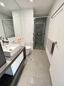 uma casa de banho com um lavatório, um chuveiro e um WC. em Spacious & Open 2 bd 2bth 2crsp apt - Dickson CBD em Camberra