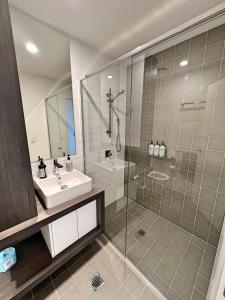 uma casa de banho com um lavatório e uma cabina de duche em vidro. em Spacious & Open 2 bd 2bth 2crsp apt - Dickson CBD em Canberra