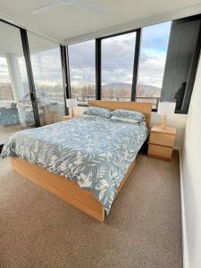 a bedroom with a bed and large windows at Spacious & Open 2 bd 2bth 2crsp apt - Dickson CBD in Canberra