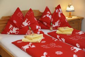 a bed with red and white blankets and pillows at Landhaus Gartler in Mauterndorf