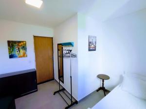 a bedroom with a bed and a door and a stool at Casa Jequitiba Quartos Mobiliados in Macaé