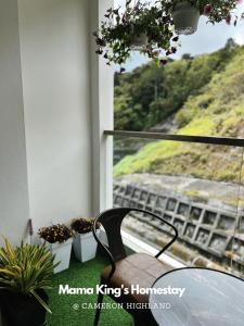 a table and chairs in front of a window with plants at Mama King’s Homestay@ Palas Horizon in Brinchang
