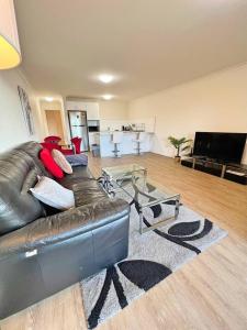 a living room with a leather couch and a television at Beautiful & enclosed, 1 bd 1 bth - close to CBR Hospital in Phillip