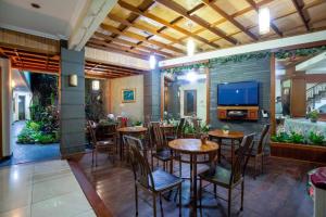 a restaurant with tables and chairs and a flat screen tv at Hotel Ardellia in Bandung