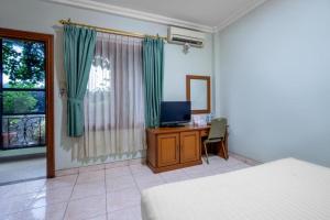 a bedroom with a bed and a desk with a television at Hotel Ardellia in Bandung
