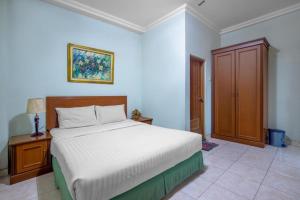um quarto com uma cama branca e um armário de madeira em Hotel Ardellia em Bandung