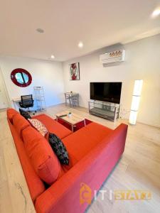 a living room with an orange couch and a flat screen tv at Enchanting in Red - 1bd 1bth 1csp in Canberra