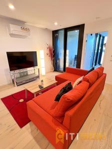 a living room with an orange couch and a television at Enchanting in Red - 1bd 1bth 1csp in Canberra