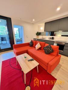a living room with an orange couch and a table at Enchanting in Red - 1bd 1bth 1csp in Canberra
