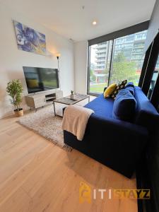 a living room with a blue couch and a large tv at Beauty in Blue! 1bd 1bth 1crsp Apt - Great Location! in Canberra
