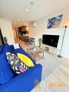 a living room with a blue couch and a tv at Beauty in Blue! 1bd 1bth 1crsp Apt - Great Location! in Canberra