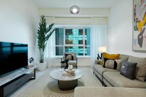 a living room with a couch and a tv at Maison Privee - Millennium Executive Tower in Dubai