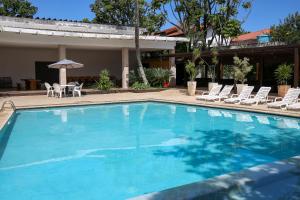 a large swimming pool with chairs and an umbrella at Golden Tulip Guarujá - Antigo Delphin Surf Hotel in Guarujá