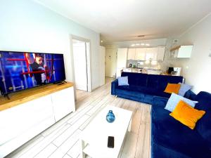a living room with a blue couch and a flat screen tv at Apartament Superior Lazurowy Przy Plaży in Kołobrzeg