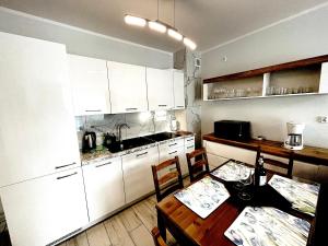 a kitchen with white cabinets and a table and chairs at Apartament Superior Lazurowy Przy Plaży in Kołobrzeg