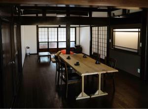 una sala da pranzo con tavolo e sedie in legno di 古民家柚子季 a Tonami
