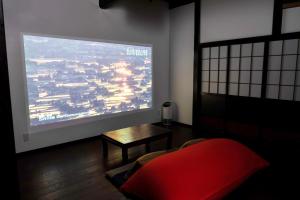una camera con una grande finestra con un letto rosso e un tavolo di 古民家柚子季 a Tonami