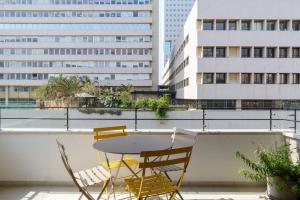 a table and chairs on a balcony with buildings at New 2bedroom apt, view to the sea and Neve Tzedek in Tel Aviv