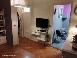 un salon avec une télévision et un bureau avec une chaise dans l'établissement Charmant et calme face gare centrale, à Nice