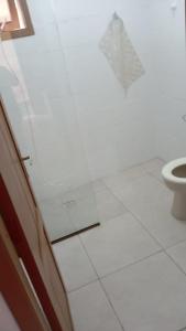 a bathroom with a toilet and a white tile floor at Casa Residencial Duque de Caxias in Arroio do Sal