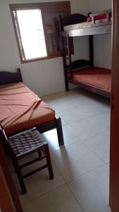 a room with two bunk beds and a chair at Casa Residencial Duque de Caxias in Arroio do Sal